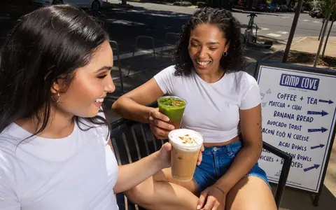 Two friends enjoying iced coffee and matcha outside Camp Cove